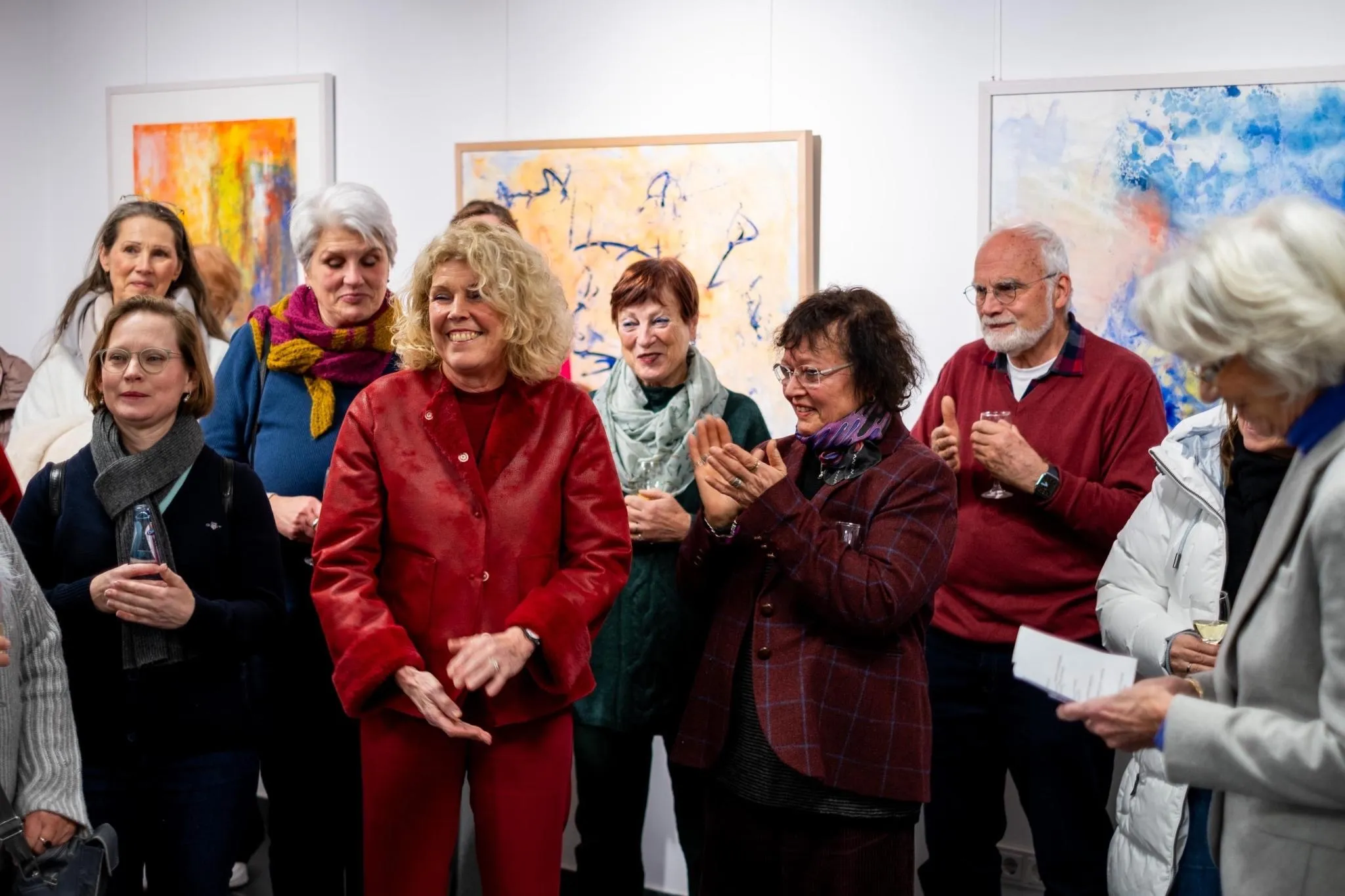 Guests applauding at the vernissage opening with artworks in the background