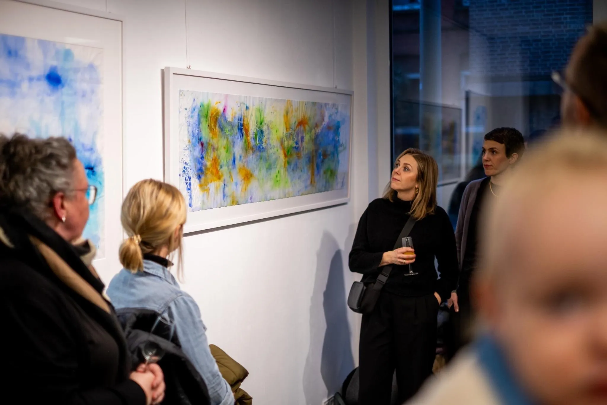 Visitors admiring colorful abstract paintings on the gallery wall