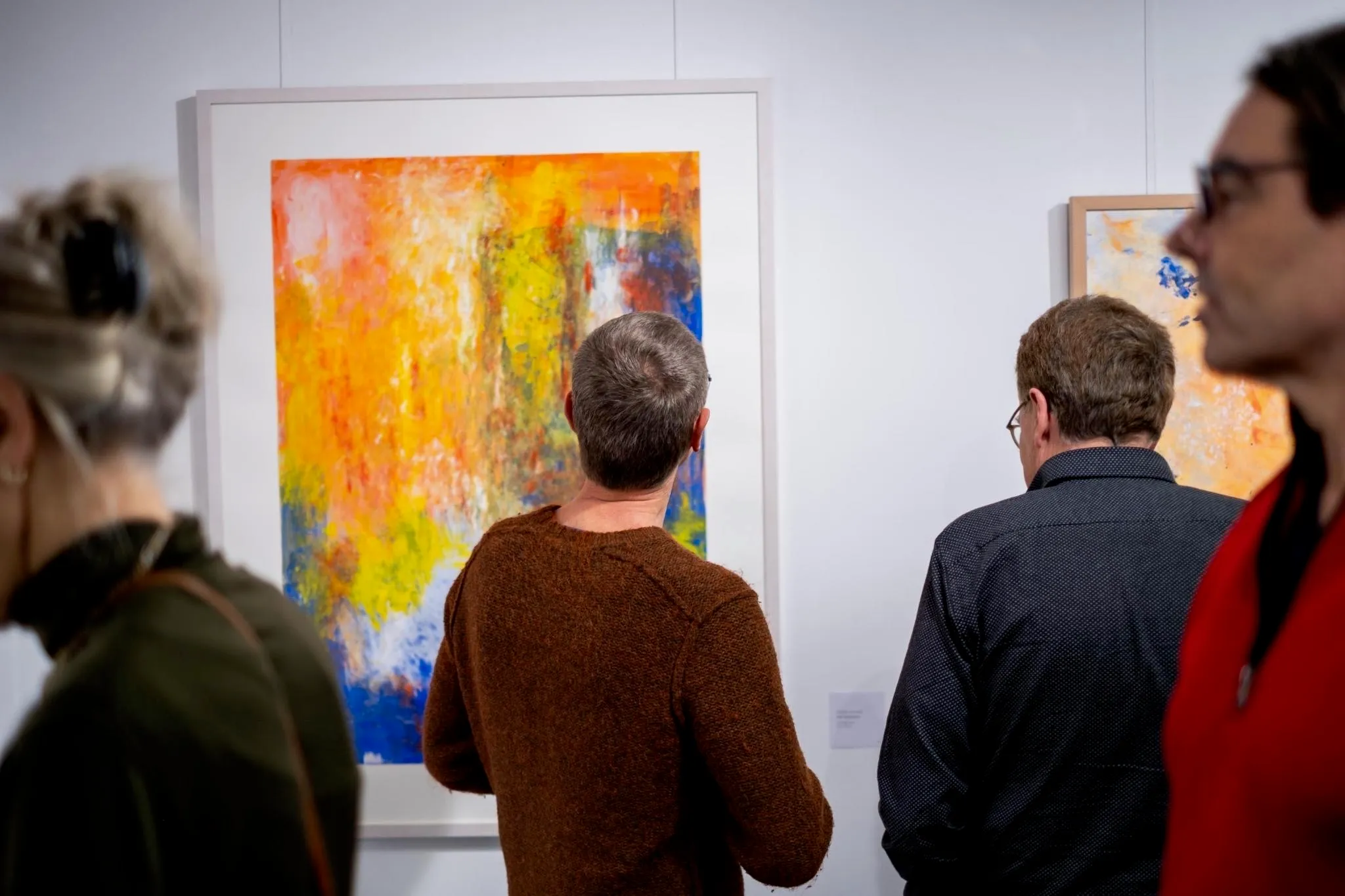 Visitors viewing a large abstract painting in orange and yellow